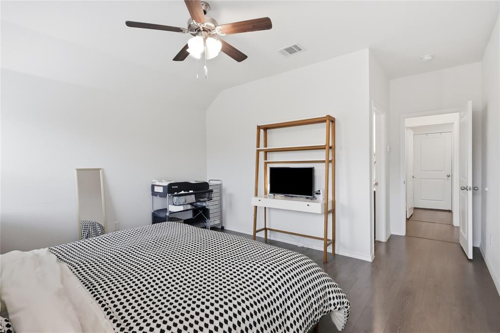 Neutral interior featuring wood-finish flooring, white walls, vaulted ceiling, and a ceiling-mounted light fixture with a fan