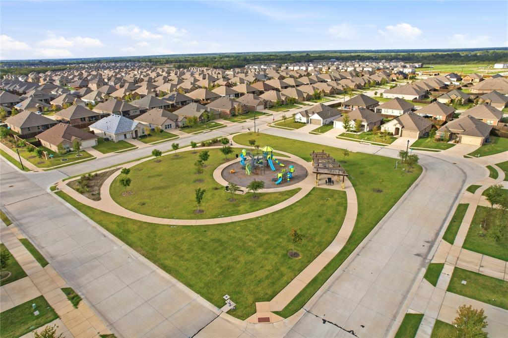 Community park featuring a central playground, covered pavilion, paved walking paths, and manicured green space