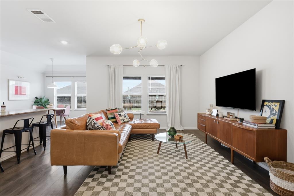 Open concept living area featuring dark wood-finish flooring, a multi-arm geometric chandelier, and a breakfast bar with stone-finish countertop