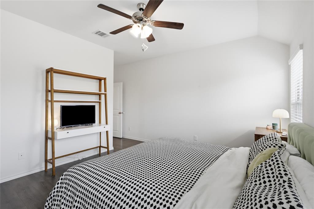 Vaulted ceiling featuring a central multi-blade ceiling fan with integrated lighting, wood-finish flooring, and window blinds