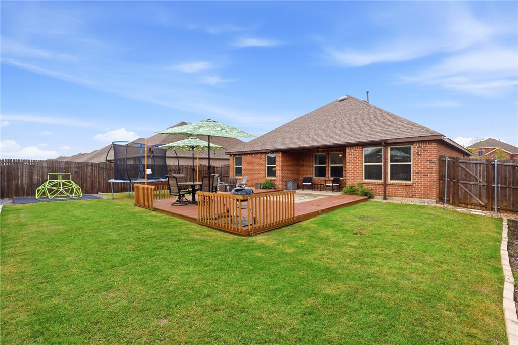 Spacious backyard featuring a brick exterior, a raised wood deck with railing, and perimeter wood privacy fencing
