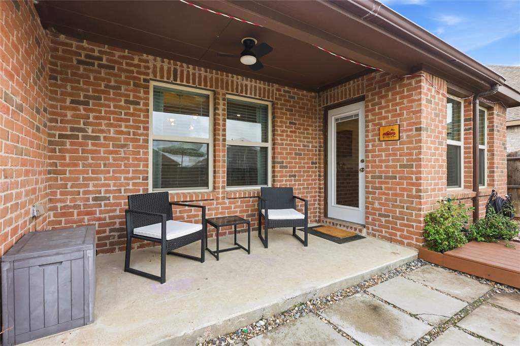 Covered brick patio featuring a concrete floor, ceiling fan, and multi-pane window configuration
