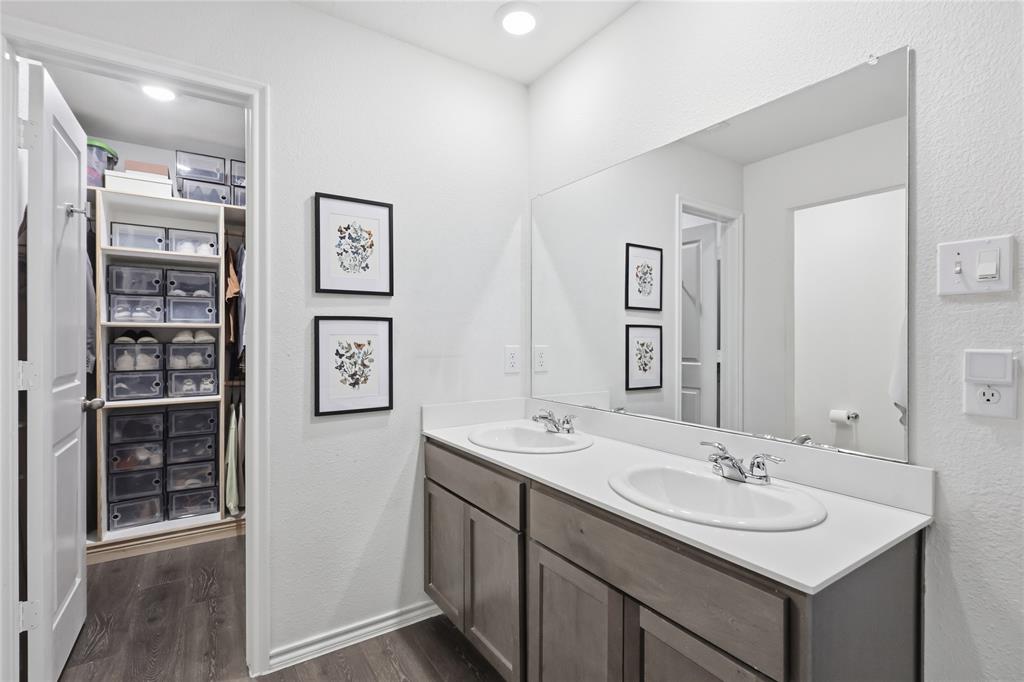 Double vanity with stone-surface countertop, dual drop-in sinks, chrome finish fixtures, and full-width wall mirror
