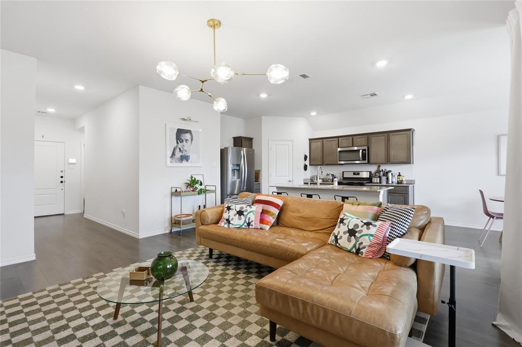 Open-concept interior featuring wood-finish flooring, a modern multi-globe chandelier, an island kitchen with stone countertops, and recessed lighting