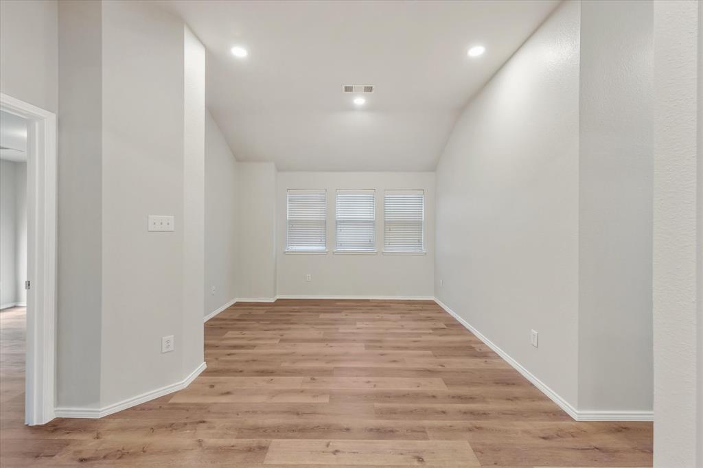Vaulted ceilings featuring recessed lighting, neutral wall finishes, and wood-finish flooring with three windows Vaulted ceilings featuring recessed lighting, neutral wall finishes, and wood-finish flooring with three windows