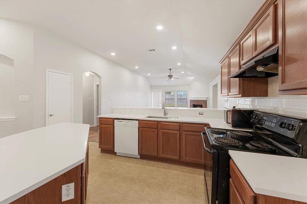 Kitchen featuring wood cabinetry, white countertops, recessed ceiling lighting, a stainless steel sink, and a black range