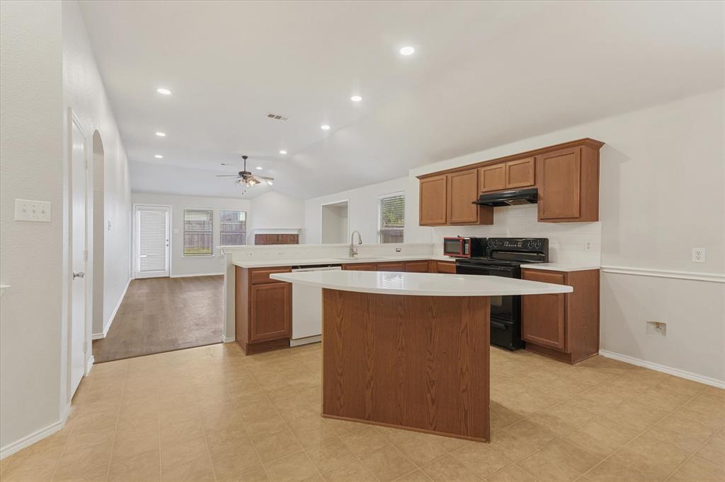 Kitchen featuring wood cabinetry, a central island with a solid-surface countertop, recessed lighting, and tile flooring Kitchen featuring wood cabinetry, a central island with a solid-surface countertop, recessed lighting, and tile flooring