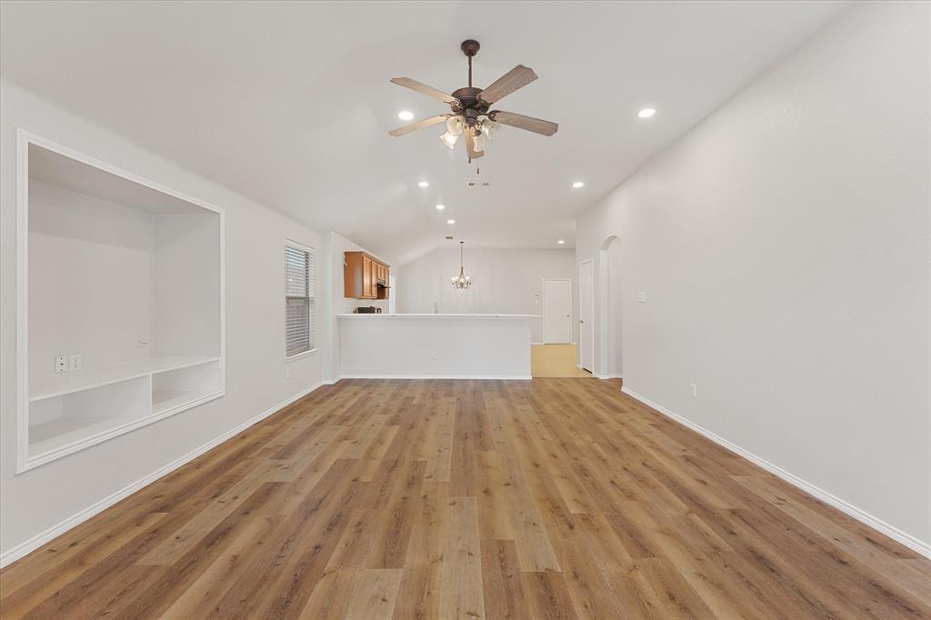 Open-concept interior featuring wood-finish flooring, vaulted ceilings, recessed lighting, a ceiling fan, and built-in shelving