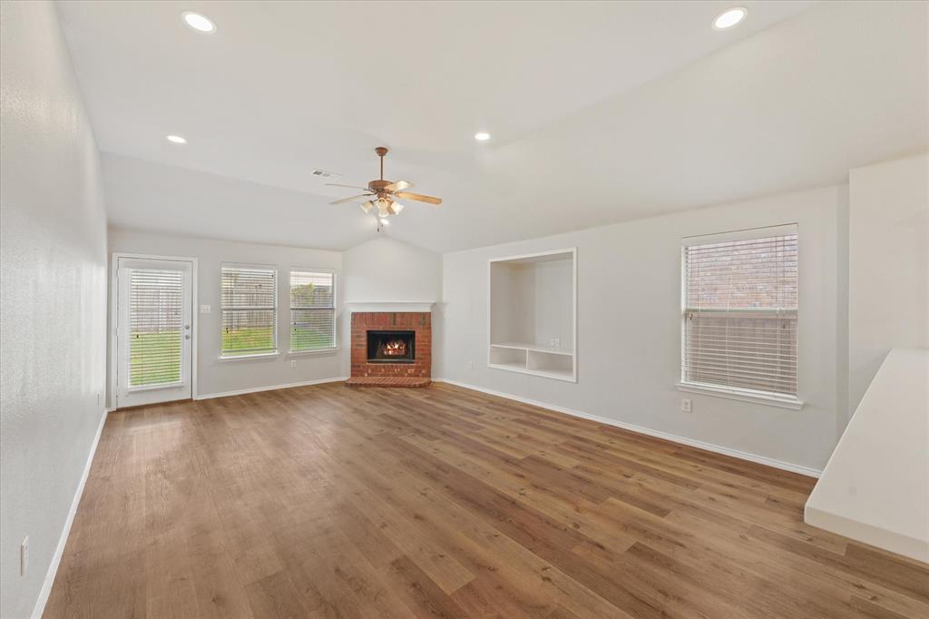 Vaulted ceilings featuring recessed lighting, wood-finish flooring, a brick fireplace, built-in shelving, and a ceiling fan