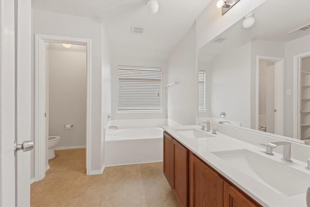 Double vanity featuring wood-finish cabinetry, quartz countertops, integrated rectangular sinks, and a full-width wall mirror