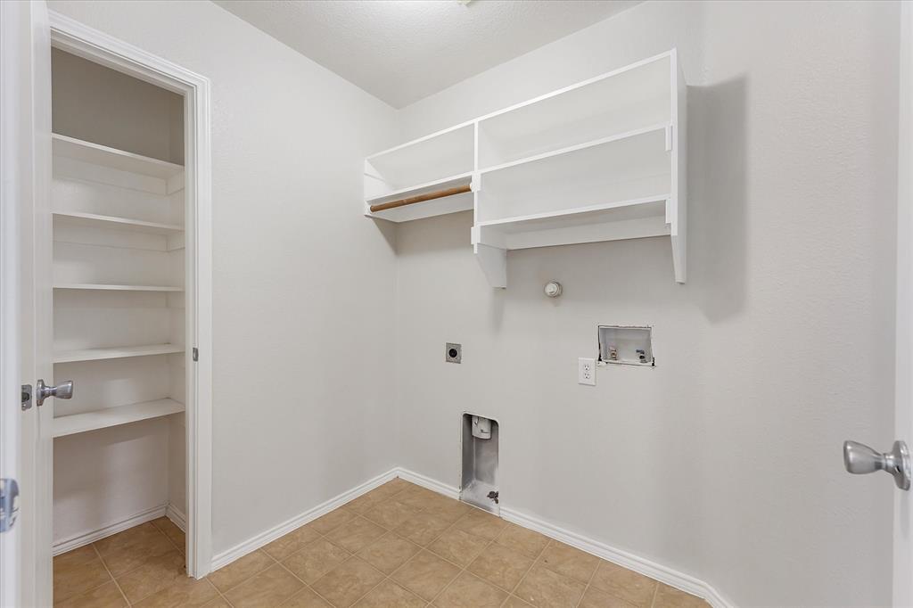 Utility space featuring ceramic tile flooring, built-in white shelving, and dual-level open storage