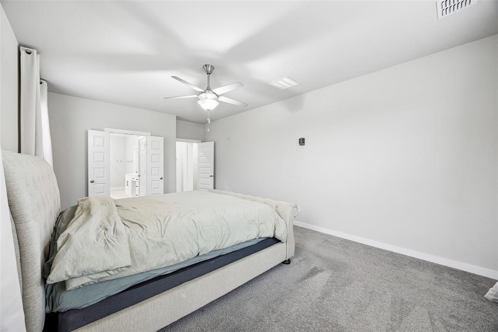 Room featuring neutral wall tones, carpeted flooring, a ceiling fan with integrated light fixture, and white dual-panel doors
