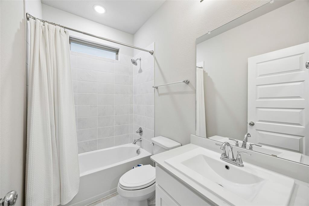 Bathroom featuring a white vanity with an integrated sink, polished chrome faucet, full-width wall mirror, and a tub-shower combination with ceramic tile surround and transom window