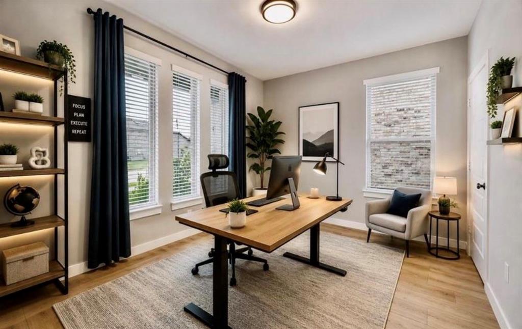 Office space featuring neutral walls, wood-finish flooring, multiple windows with blinds, and built-in wall shelving with integrated lighting