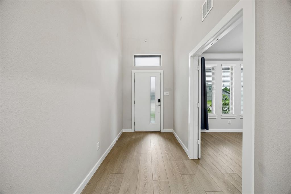 Entryway featuring high ceilings, wood-finish flooring, a front door with a vertical glass insert, and a transom window
