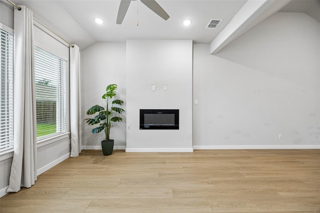 Vaulted ceilings, wood-finish flooring, recessed lighting, ceiling fan, and built-in electric fireplace
