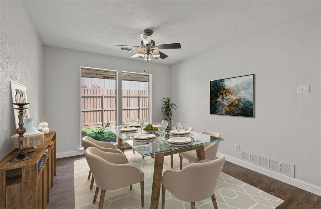 Neutral interior space featuring wood-finish flooring, dual windows providing exterior exposure, and a ceiling-mounted light fixture with a central fan