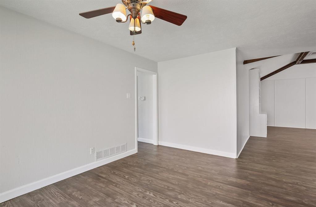 Wood-finish flooring, neutral wall tones, multi-light ceiling fan, and exposed structural ceiling beams