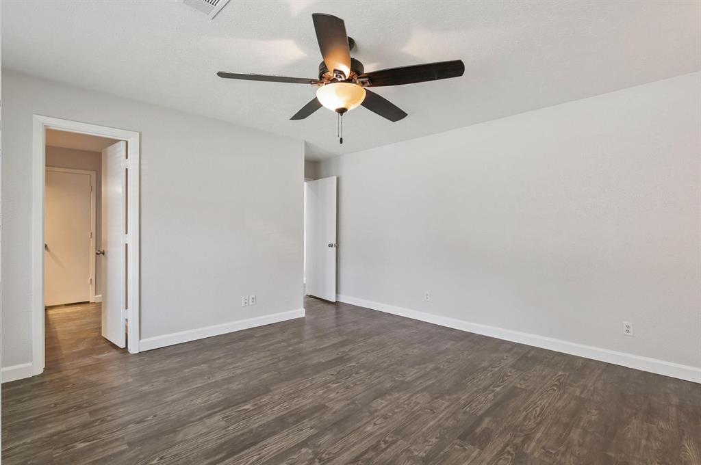 Wood-finish flooring, neutral wall tones, and a ceiling fan with integrated light fixture