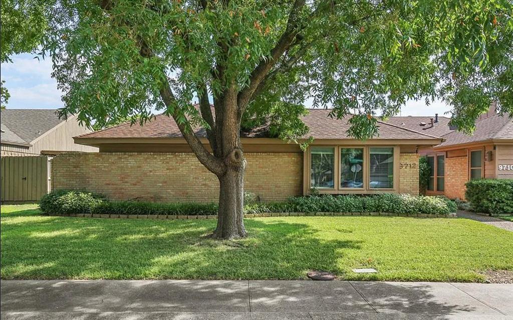 Single-story brick exterior featuring a low-pitch roof, expansive front lawn, mature tree, and bay window