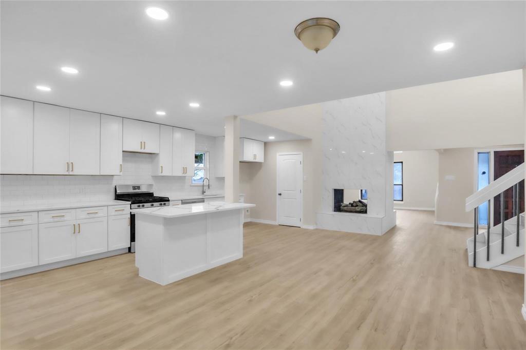 Kitchen featuring white shaker-style cabinetry, a central island with countertop, and wood-finish flooring