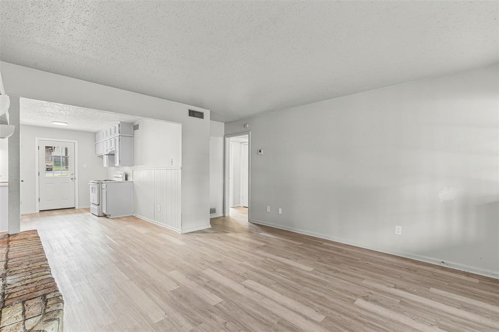 Unfurnished living room with light wood-style flooring and a textured ceiling