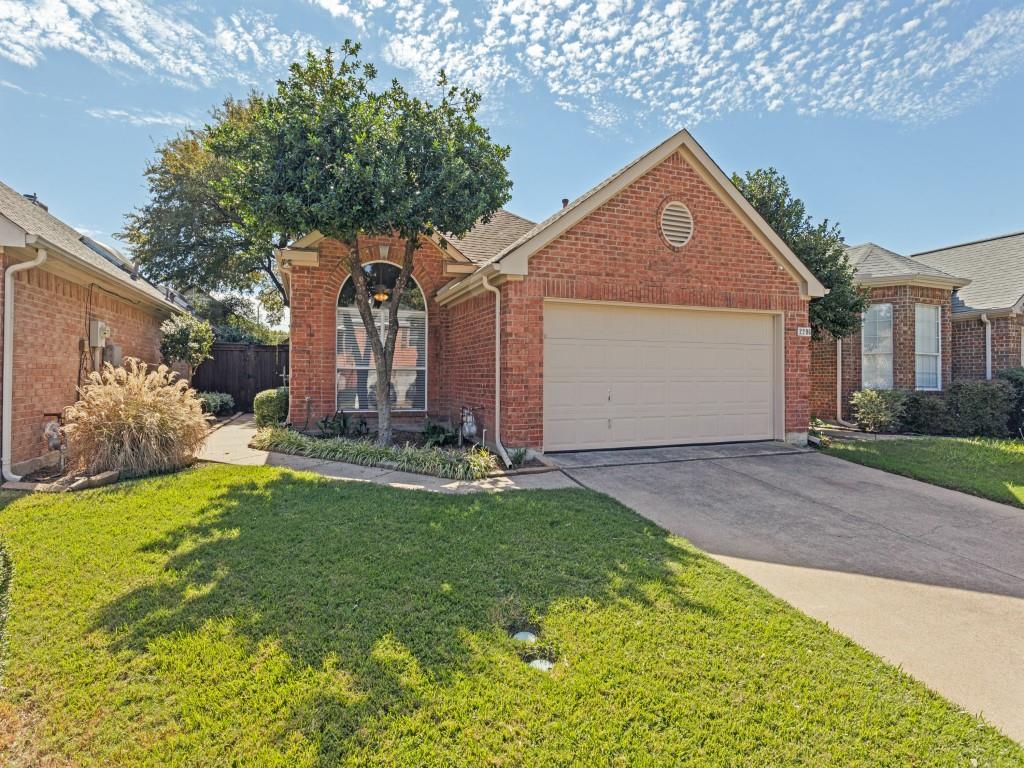 Brick exterior featuring a front-facing attached garage, arched window, gable roofline, and concrete driveway Brick exterior featuring a front-facing attached garage, arched window, gable roofline, and concrete driveway
