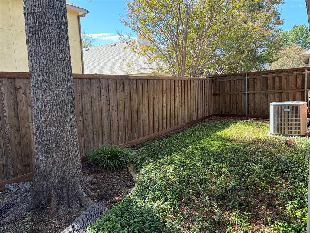 Private backyard featuring a full-perimeter wood fence, mature tree, patio and  established ground cover.