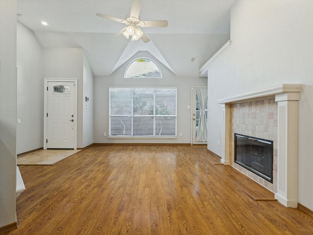 Vaulted ceilings, laminate flooring, fireplace with a tile surround and mantel, arched window, and central ceiling fan Vaulted ceilings, laminate flooring, fireplace with a tile surround and mantel, arched window, and central ceiling fan