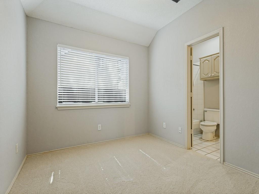 Neutral carpeting, and horizontal blind, doorway into a tiled bathroom with built-in cabinetry Neutral carpeting, and horizontal blind, doorway into a tiled bathroom with built-in cabinetry