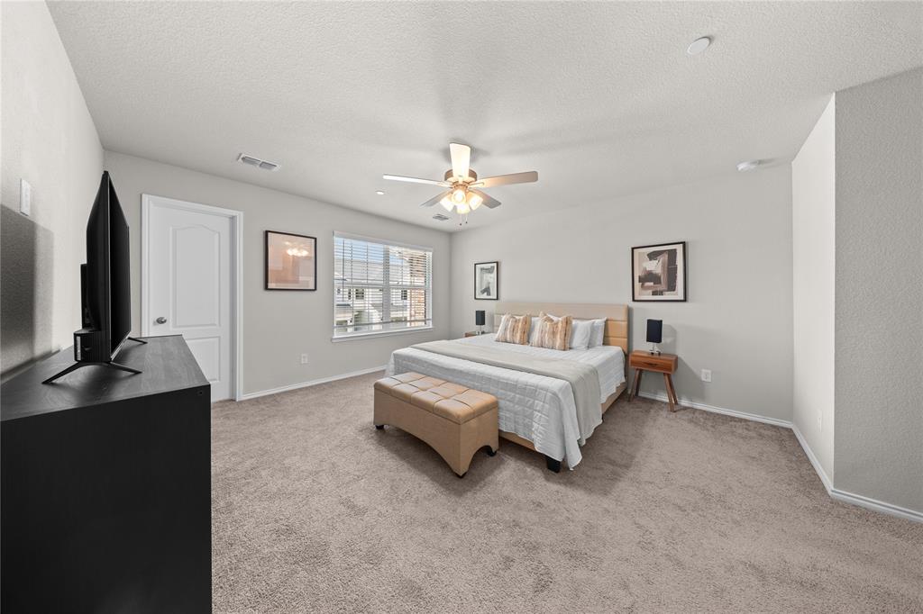 Spacious interior featuring neutral wall tones, wall-to-wall carpeting, a multi-blade ceiling fan with integrated light fixture, and a white six-panel door