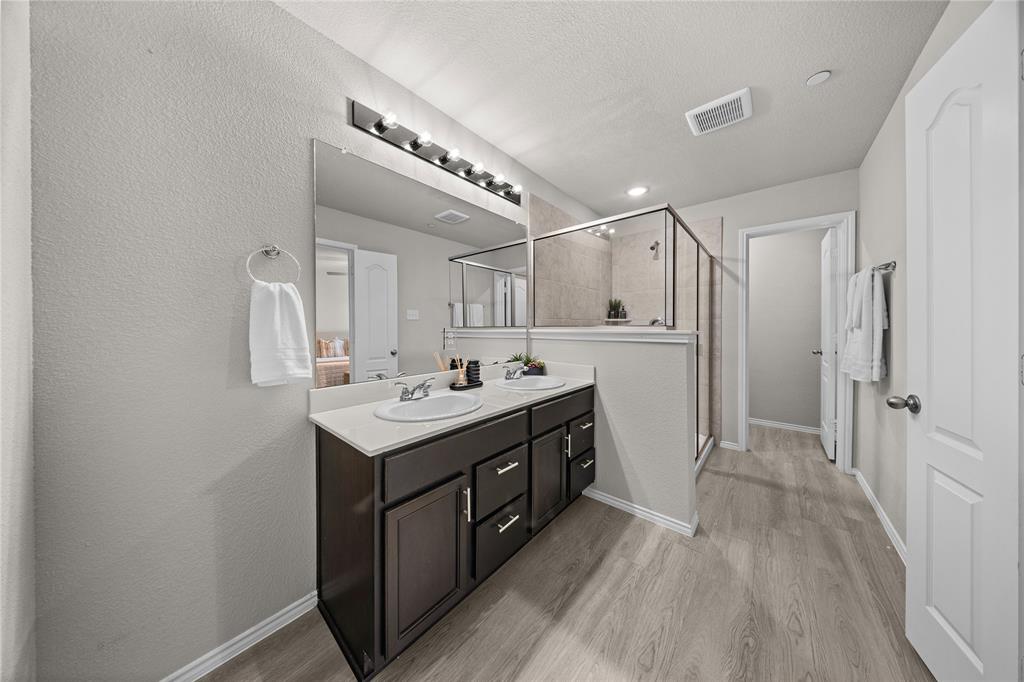 Double vanity featuring dark cabinetry, solid-surface countertop, dual recessed sinks, and a full-width mirror