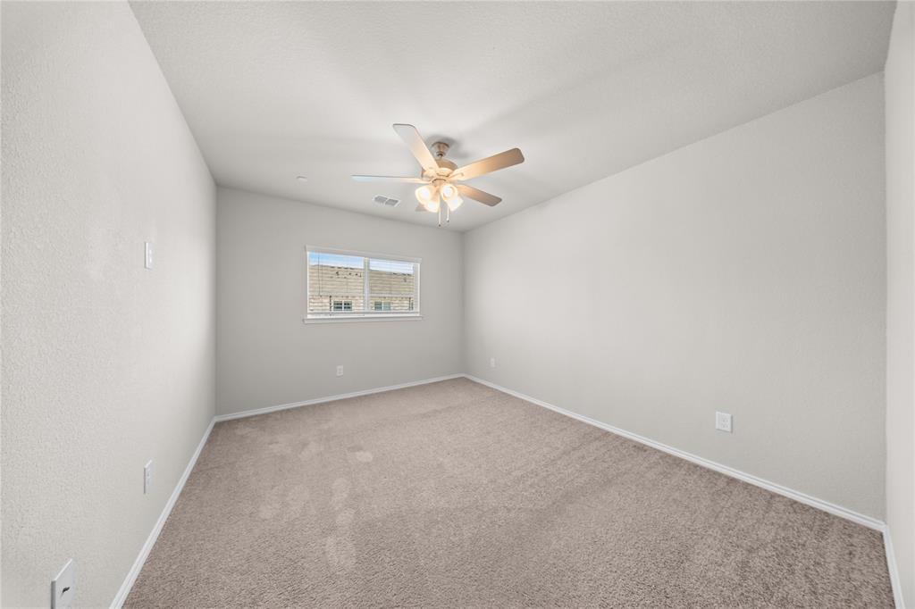 Neutral-toned interior space featuring light-colored wall paint, wall-to-wall carpeting, and a ceiling-mounted fan with integrated light fixture