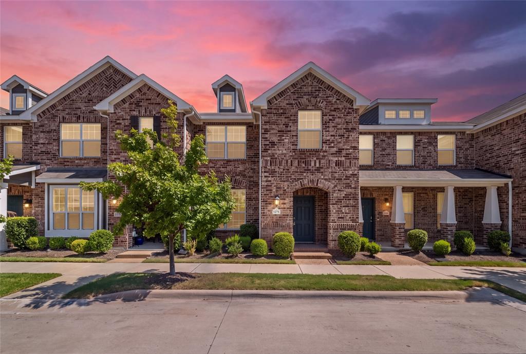 Multi-story brick exterior featuring steep gabled rooflines, decorative dormer windows, covered entryways with square columns, and uniform multi-pane windows