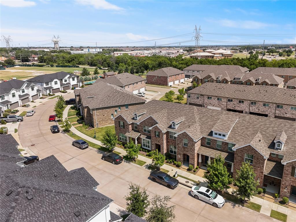 Multi-level residential structures featuring brick masonry facades, steeply pitched shingled roofs, dormer windows, and attached garages