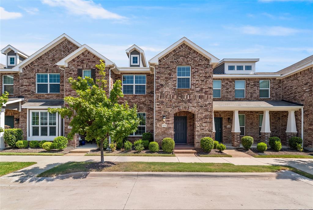 Multi-story brick exterior featuring gable rooflines, multipane windows, and covered porches supported by square columns