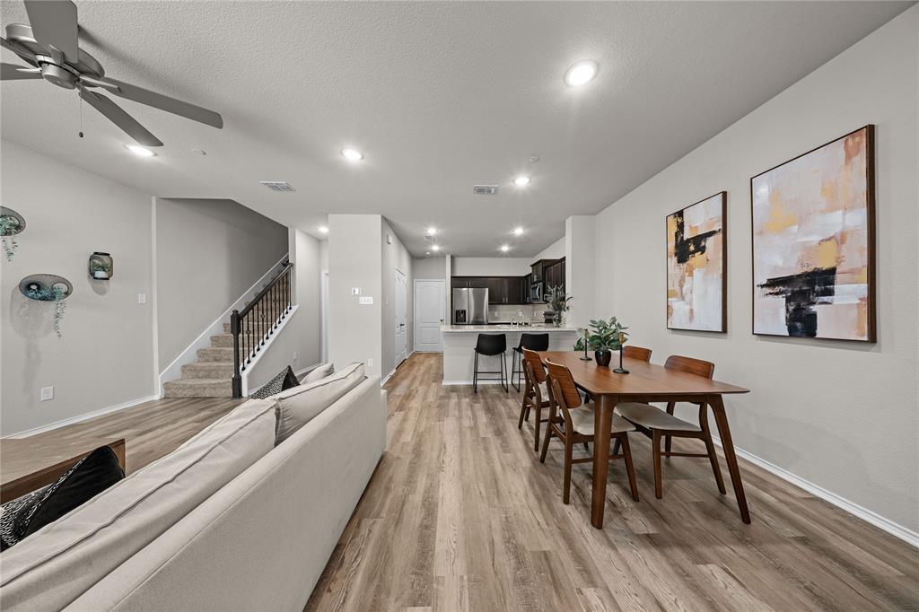 Open-concept area featuring wood-finish flooring, recessed lighting, a ceiling fan, and a kitchen island with stone-finish countertops