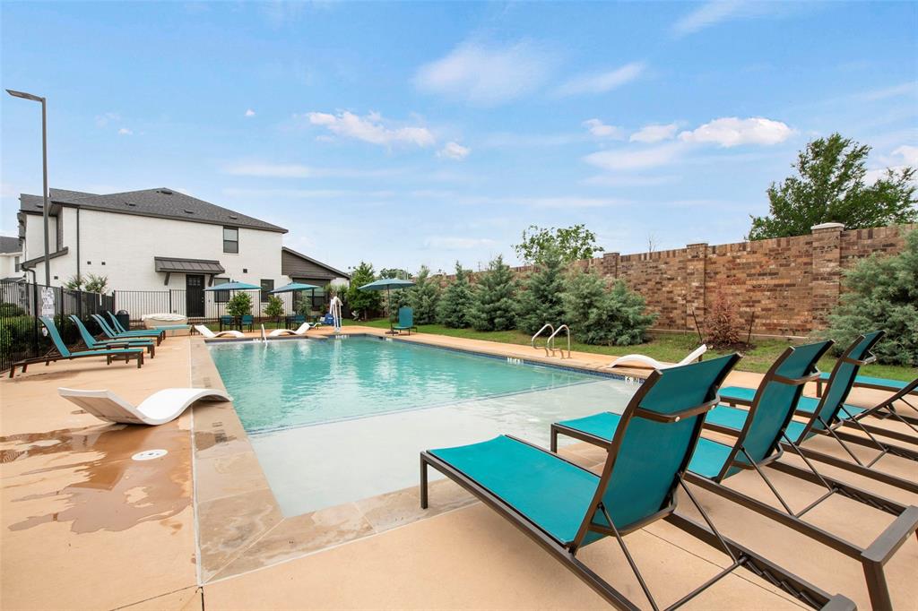 Swimming pool with a baja shelf, concrete decking, and brick privacy wall