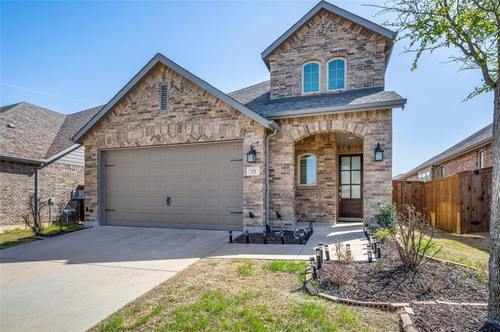 French country home with driveway, brick siding, a shingled roof, covered porch, and an attached garage