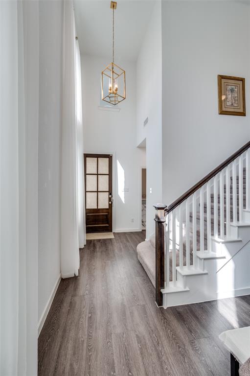Foyer entrance featuring wood finished floors, a towering ceiling, stairs, and a chandelier