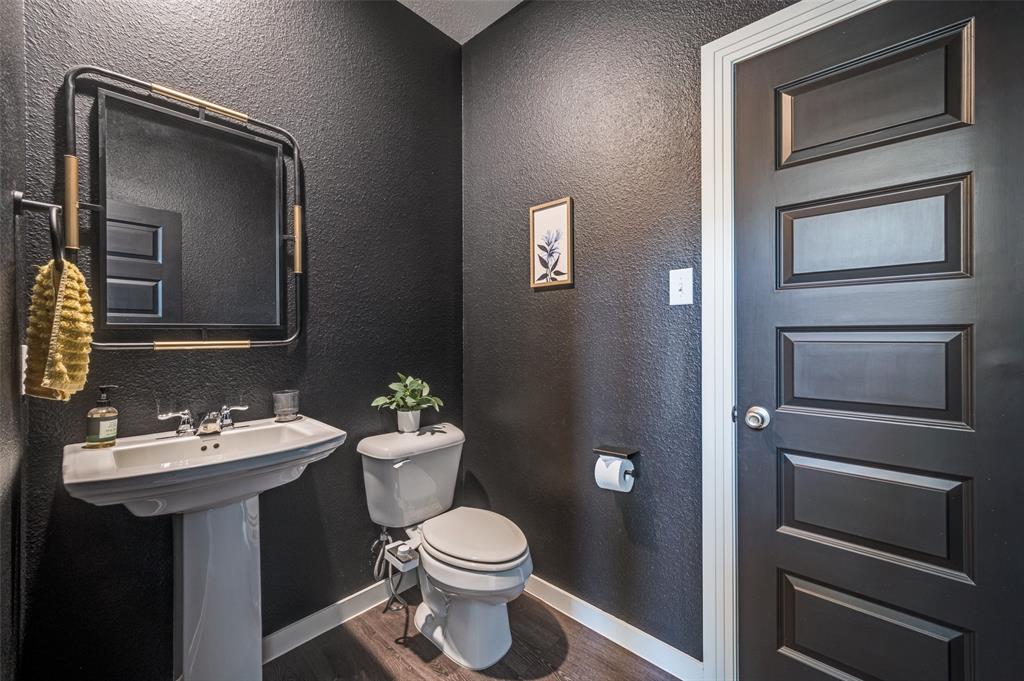Half bath with a textured wall and dark wood finished floors