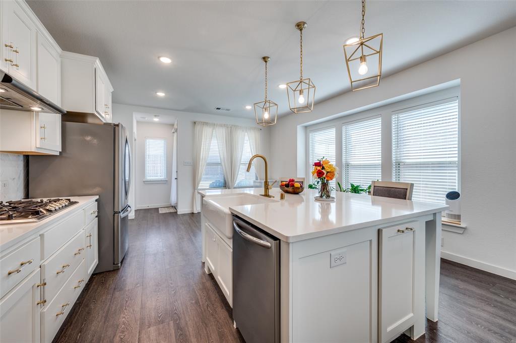 Kitchen with white cabinetry, stainless steel appliances, pendant lighting, a center island with sink, and dark wood-style flooring