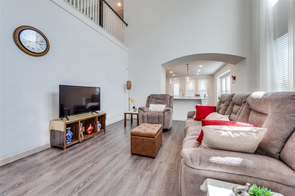 Living area featuring arched walkways, wood finished floors, recessed lighting, and a high ceiling