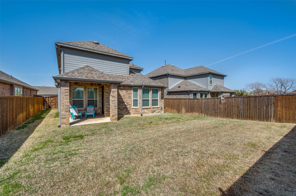 Back of property with a fenced backyard, a patio, brick siding, and roof with shingles