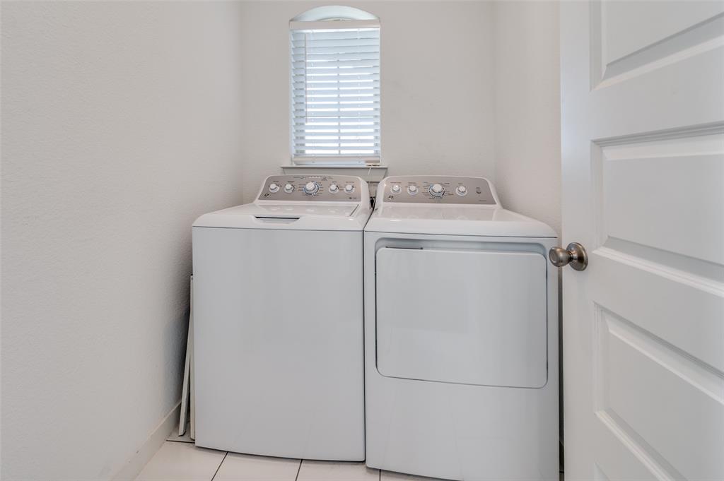 Washroom with light tile patterned floors and washer and clothes dryer