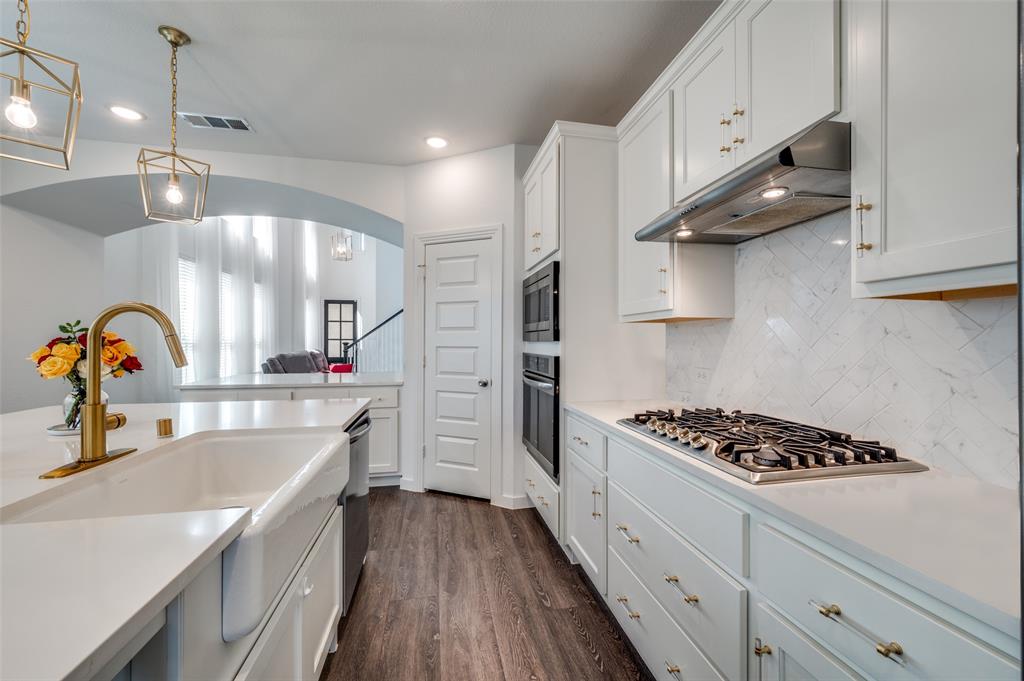 Kitchen with pendant lighting, backsplash, white cabinetry, dark wood finished floors, and under cabinet range hood