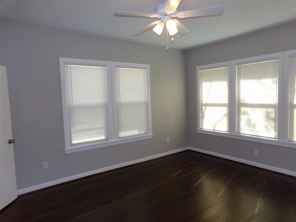 Room featuring dark wood-finish flooring, multi-pane windows, and a ceiling-mounted light fixture with a fan
