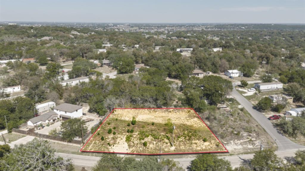 Expansive, cleared rectangular parcel featuring native vegetation, mature trees, and direct street access