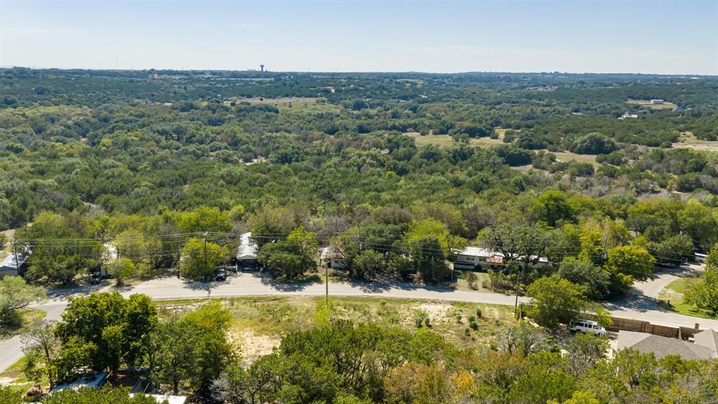 Aerial perspective of the lot featuring expansive natural terrain, mature tree canopy, and established paved road access