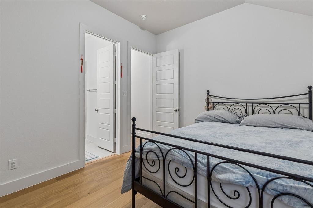 Room featuring wood-finish flooring, vaulted ceilings, and five-panel interior doors